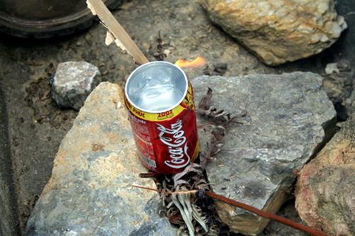 Không có nồi thì dùng tạm lon coca nấu nước - Ảnh: Thủy Trần