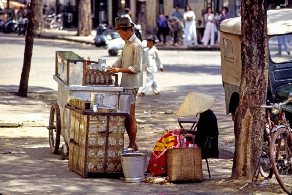 Một xe đẩy bán nước bên cạnh một quầy cà phê nhỏ trên vỉa hè Sài Gòn.