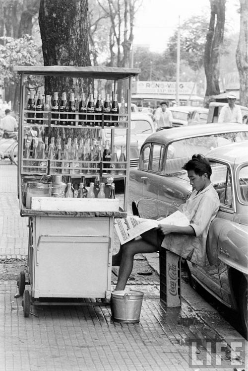 Cậu bé bán nước lấy khay nước ngọt làm ghế ngồi.
